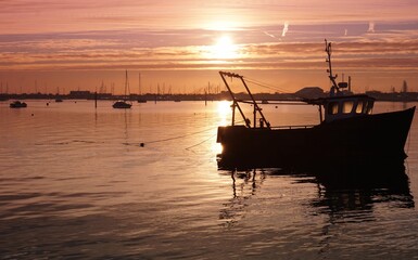Silhouette of a wooden ship floating on the water surface in the Langstone harbor in Hampshire