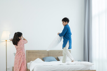Indian family, brother and sister with traditional clothes having fun playing pillow fight, two...