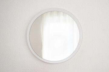 Round gold mirror on the white wall 