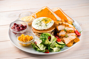 American breakfast with fried eggs, pancakes, salad, toast