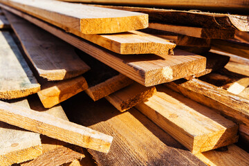 Wooden boards are randomly stacked on a construction site. Material for carpentry and construction work. Close up