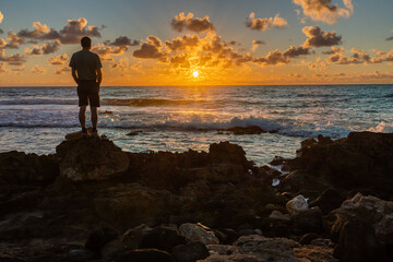 Man, person, silhouette, standing on basalt rocks from an ancient lava flow by the edge of the...