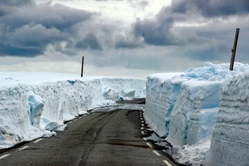 Empty road running between the masses of snow.