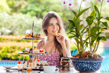 Woman eat macaroon, desserts assortment in outdoor resort restaurant