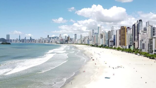 Bird's eye view of ocean waves against Santos beach with modern skyscrapers in Sao Paulo, Brazil