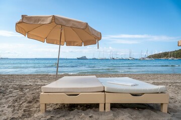 Sandy beach with beds and umbrellas with a cloudy blue sky in the background, Salines, Ibiza, Spain
