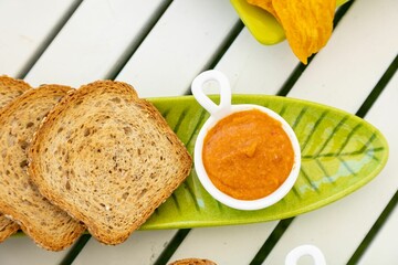 Top view of catering of sliced brown bread with dipping sauce in a leaf-formed green plate