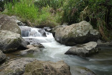 River water flowing on hug rocks, long exposure effect