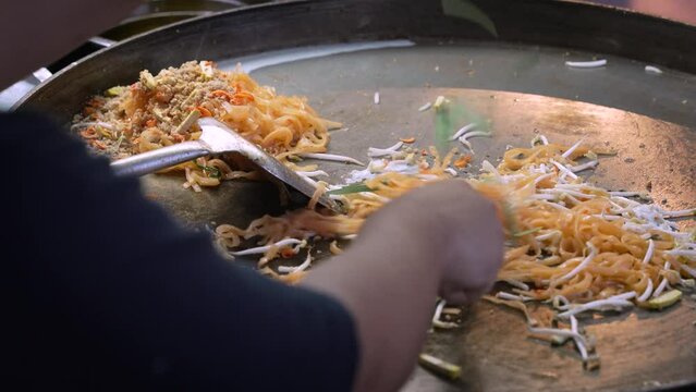 Pad Thai Bangkok Street food being cook on a flat Thai Wok with another order being ready on the side.