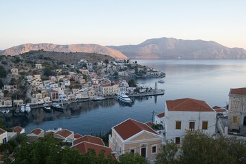 Fototapeta na wymiar Beautiful view of the Symi Harbor on Symi Island, Greece with boats docked on calm waters at sunset