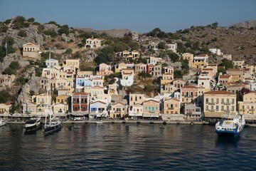 Beautiful view of the Symi Harbor on Symi Island, Greece with boats docked on calm waters at sunset