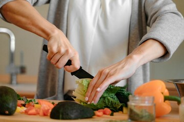 Chef using a steel knife to slice a garbage and a yellow pepper in the kitchen on the table