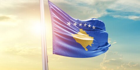 Waving Flag of Kosovo in Blue Sky. The symbol of the state on wavy cotton fabric.