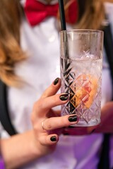 Vertical shot of a hand of a woman holding a drink with a grapefruit and black straw