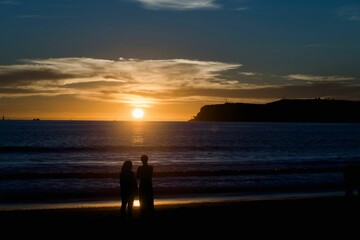 Silhouettes of women standing before the seascape enjoying the sunset