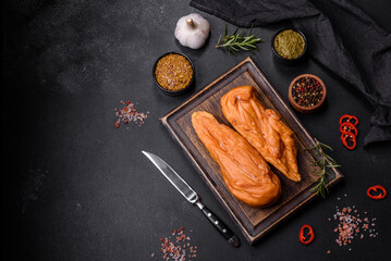 Tasty smoked fillet of chicken breast with spices and herbs on a wooden cutting board