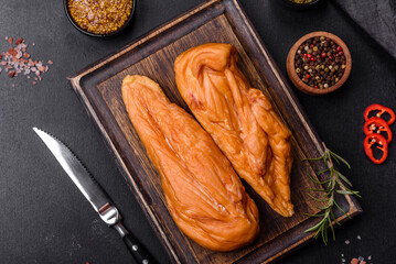 Tasty smoked fillet of chicken breast with spices and herbs on a wooden cutting board