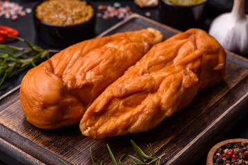 Tasty smoked fillet of chicken breast with spices and herbs on a wooden cutting board