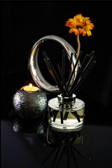Vertical shot of a candle with aromatic diffuser and modern vase with yellow flower