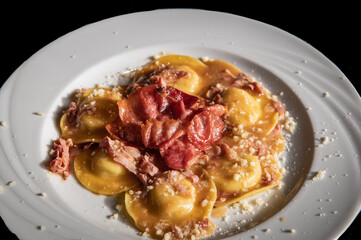 Handmade agnolotti with speck, type of ravioli, typical Italian egg pasta from Piedmont region, northern Italy - Selective focus with shallow depth of field