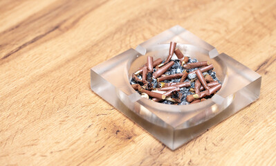 A lot of burnt cigarette butts with ashes in an ashtray close-up. The concept of the dangers of...