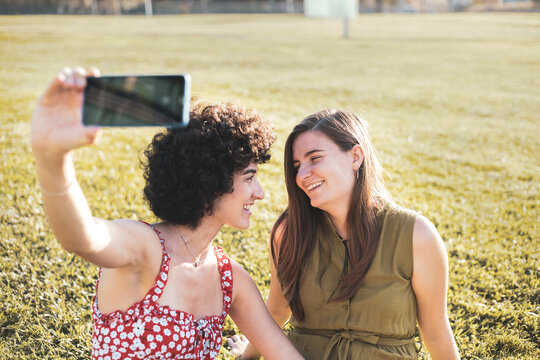 Some lesbian girls take a picture with their mobile while they look at each other in an outdoor park.Save moments as a couple, have fun.