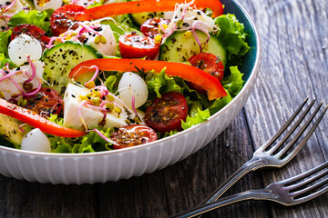 Tasty salad - manouri cheese and fresh vegetables on wooden table
