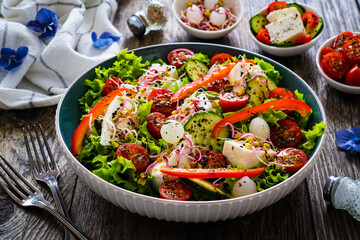 Tasty salad - manouri cheese and fresh vegetables on wooden table
