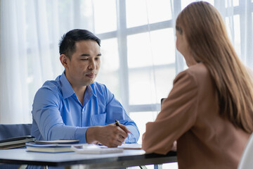 Asian male businessman and female accountant meeting financial budget, financial graph analysis with laptop, calculate with calculator in office.