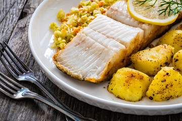 Fish dish - fried halibut with French fries and lemon on wooden table
