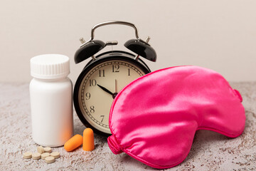 Sleeping mask, alarm clock, insomnia pills and ear plugs on a white  background. The concept of rest, sleep quality, good night, insomnia and relaxation. View from above. flat lay