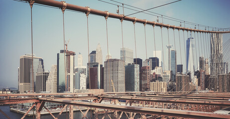 Retro toned picture of New York cityscape seen through Brooklyn Bridge cables, USA.