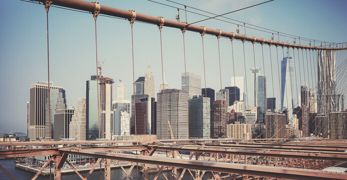 Fototapeta Retro toned picture of New York cityscape seen through Brooklyn Bridge cables, USA.