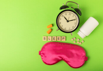 Sleeping mask, alarm clock, pills, ear plugs and the inscription SLEEP on a green background. The...