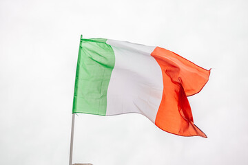 Flag of Italy on the flagpole fluttering in the wind against the blue sky.