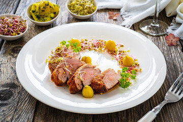 Fried pork loin with fresh vegetables on wooden table
