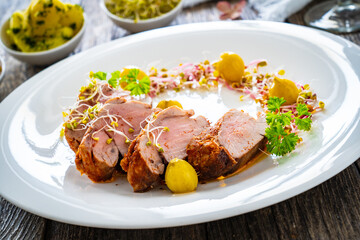 Fried pork loin with fresh vegetables on wooden table
