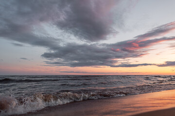 Fototapeta na wymiar Orange sunset on the mediterranean sea, waves with golden sand. Pink clouds.