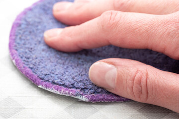 General house cleaning. Wiping the surface from dust with a purple rag, sponge. The hand of a housewife wipes the surface with an absorbent cloth.
