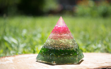 Rosa grüne Orgonit Pyramide auf Holz in Wiese