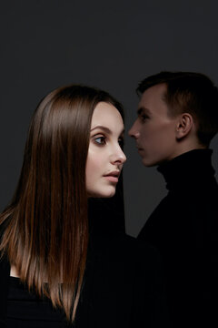 Beautiful young lovers man and woman couple on dark background. Fashion studio photo of beautiful couple. Love. Facial profile close up.