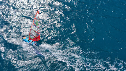 Aerial frone view photo of fit man practising wind surfing in Mediterranean bay with crystal clear deep blue sea