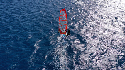 Aerial drone photo of wind surfer cruising in high speed in tropical ocean bay with deep blue see