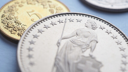 Swiss coins lie on light blue surface. 1 one frank coin close-up. Illustration about economy, business or swissy. Money and currency of Switzerland. Obverse of coin with figure of Helvetia. Macro