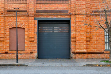Fototapeta na wymiar Red brick wall with automatic metal roller doors used in factory, warehouse, garage.