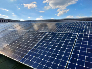 Solar panels on the roof of a building during sunny weather. The surface of the panels has blue...