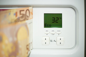 Euro bills on the door of the heating boiler with digits of the temperature of the thermostat.