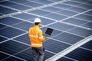 Solar energy worker or engineer with his laptop computer checking installation and productivity of...