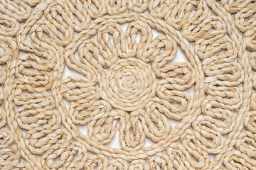 Round woven natural straw placemat on a white background. Beige background