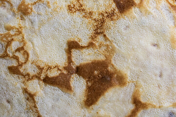 Pancake surface texture and pattern. Close-up of thin hot pancakes in a plate. Traditional rustic food. Graphic resource.